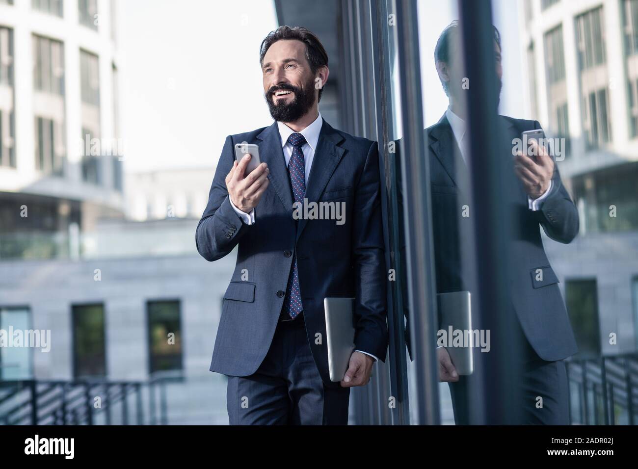 Optimistic handsome businessman using his smartphone with pleasure Stock Photo