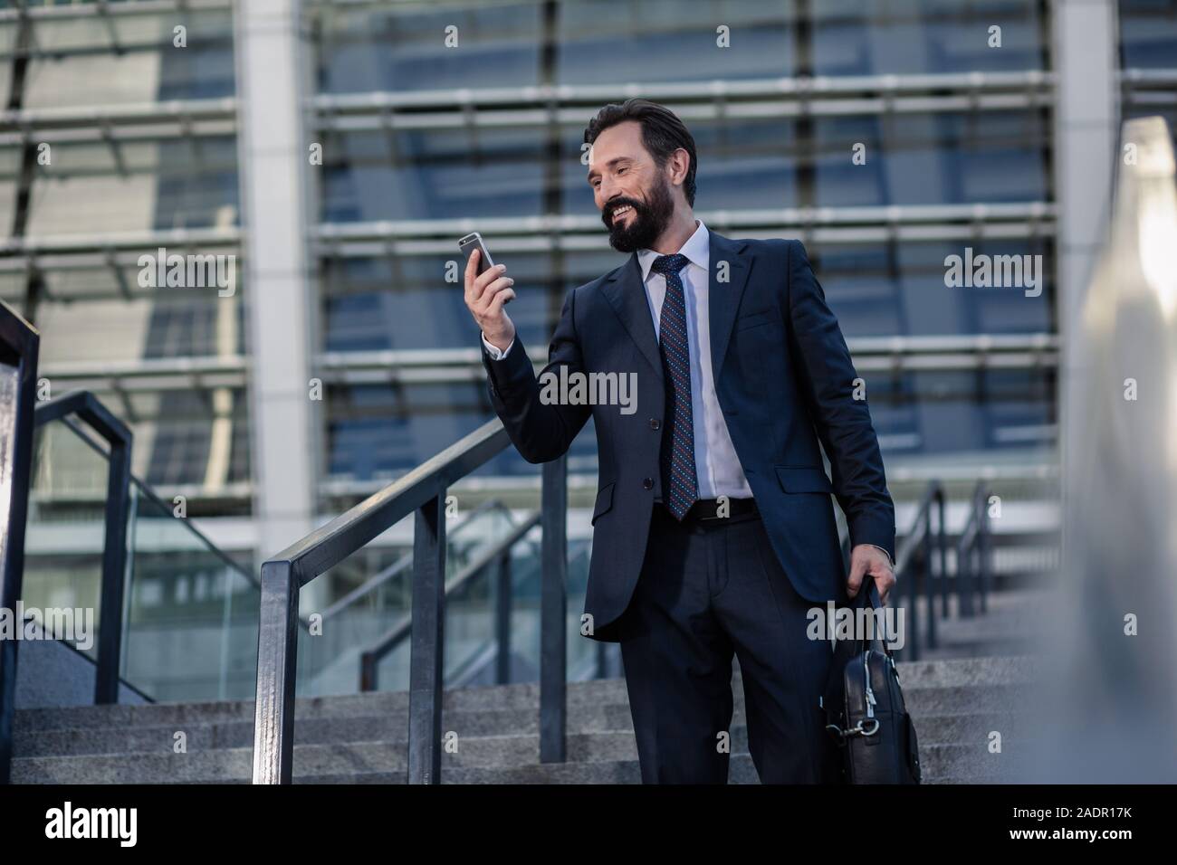 Delighted smiling businessman using his smartphone outdoors Stock Photo