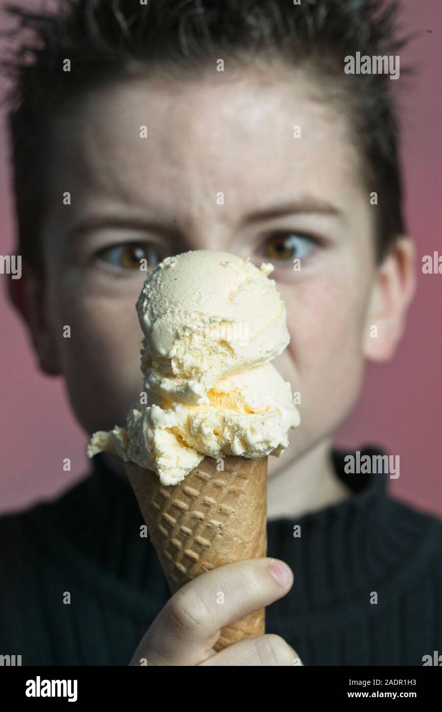 Young boy looking cross side add to scoop vanilla ice cream cone Stock Photo