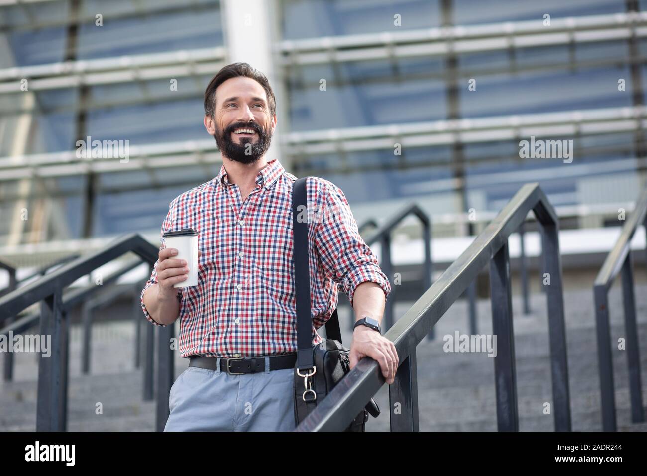 Optimistic handsome man walking down the stairs Stock Photo