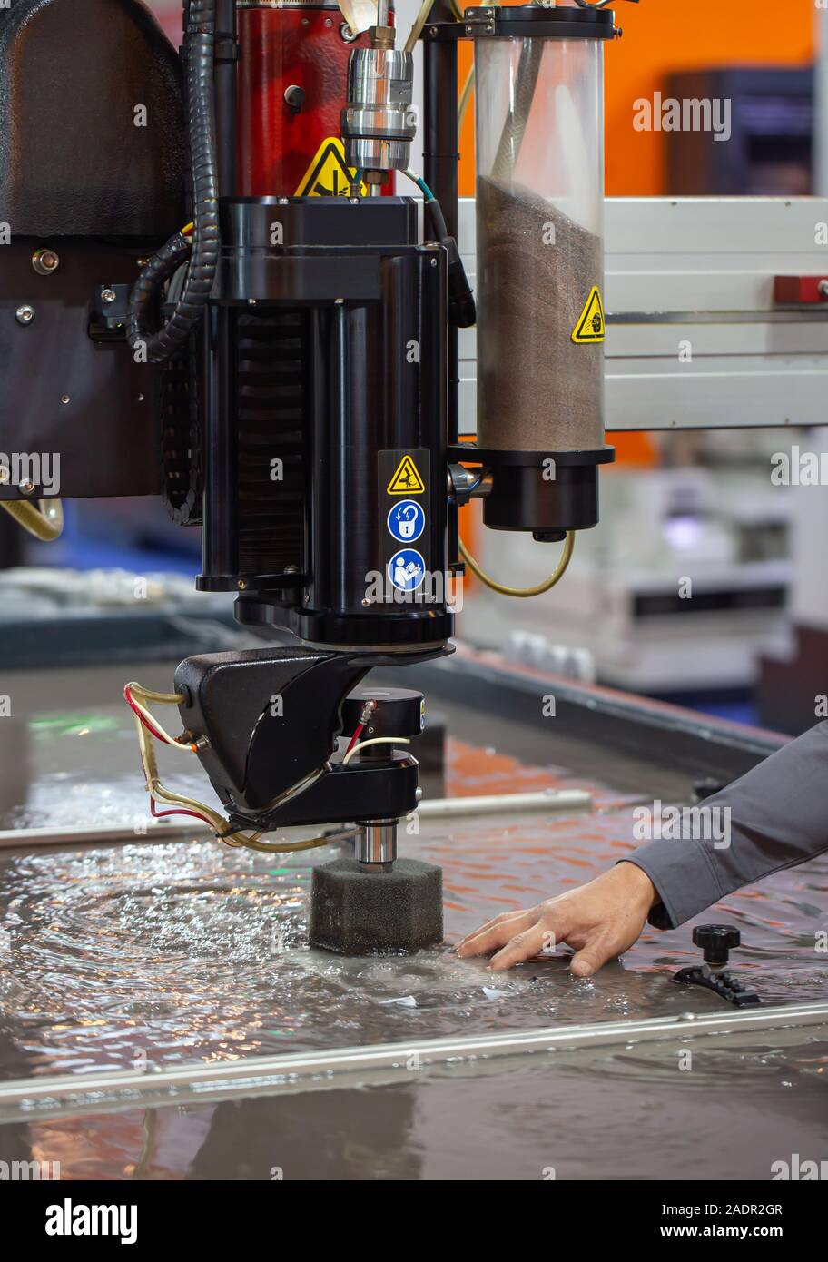 Industry worker operating CNC abrasive water jet cutting machine Stock