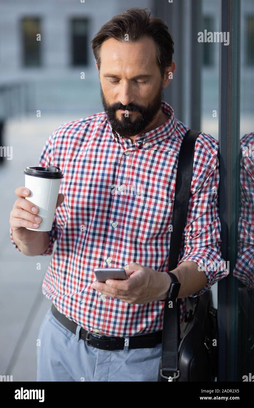 Concentrated bearded man using his mobile phone Stock Photo