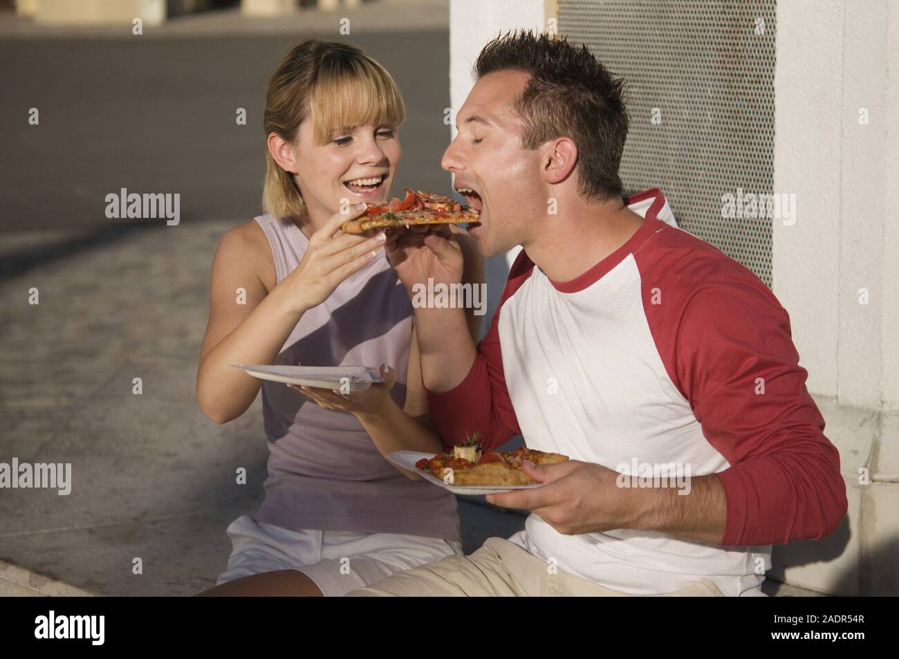 Junges Paar isst eine Pizzaschnitte - Young couple eating pizza outdoors Stock Photo