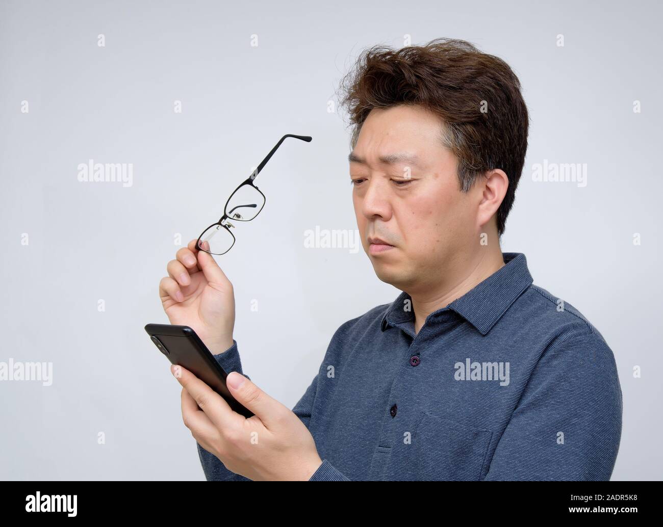 Asian male trying to read something on his mobile phone. poor sight, presbyopia, myopia. Stock Photo