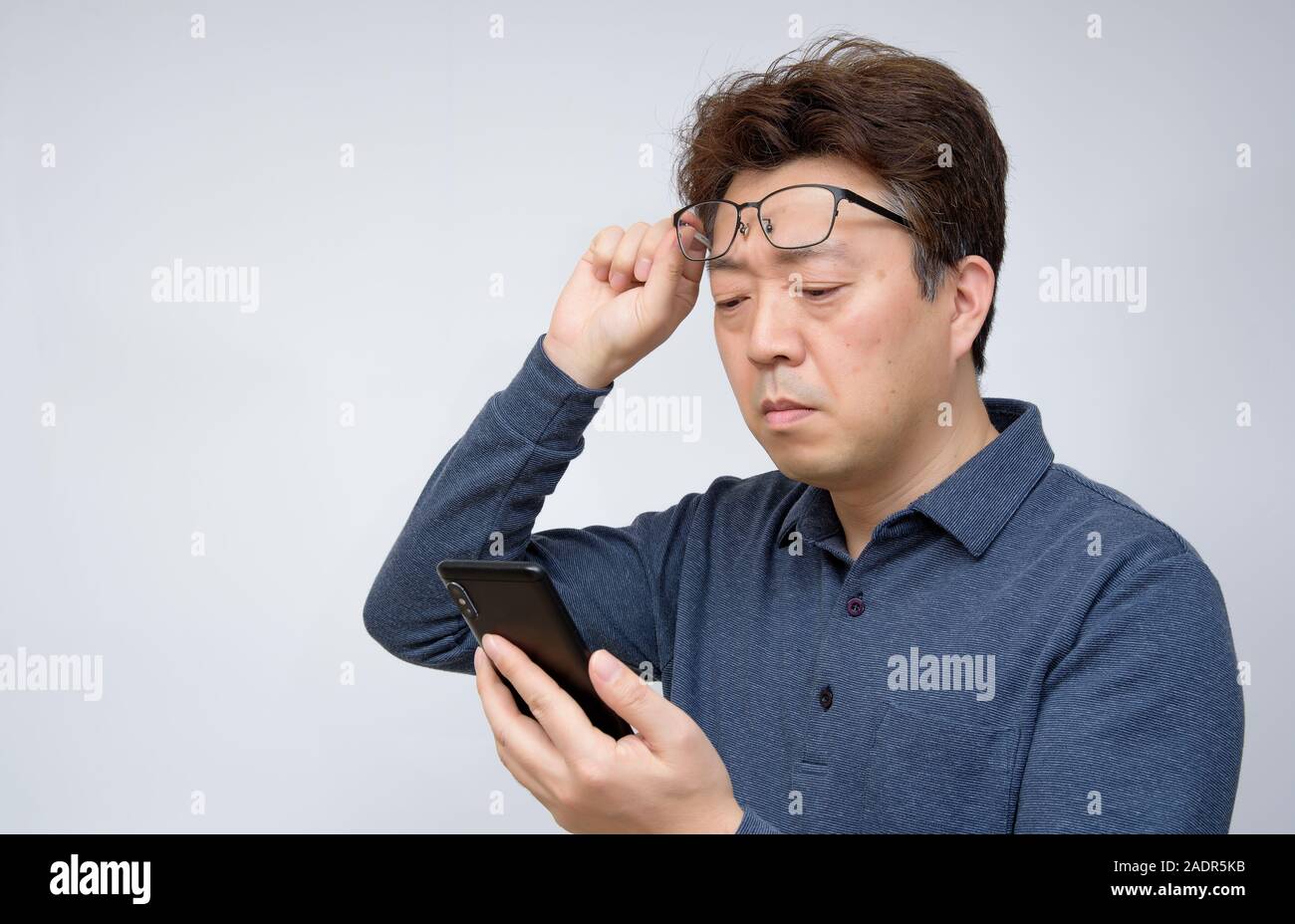Asian male trying to read something on his mobile phone. poor sight, presbyopia, myopia. Stock Photo