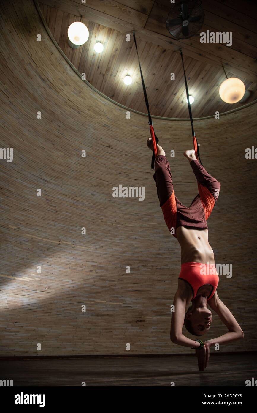 Woman practicing aerial yoga with special straps Stock Photo