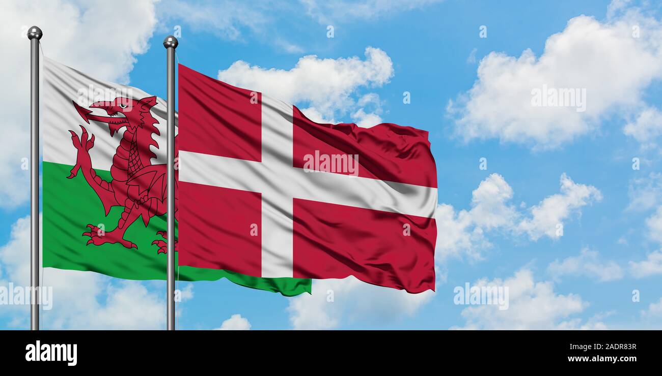 Wales and Denmark flag waving in the wind against white cloudy blue sky together. Diplomacy concept, international relations. Stock Photo