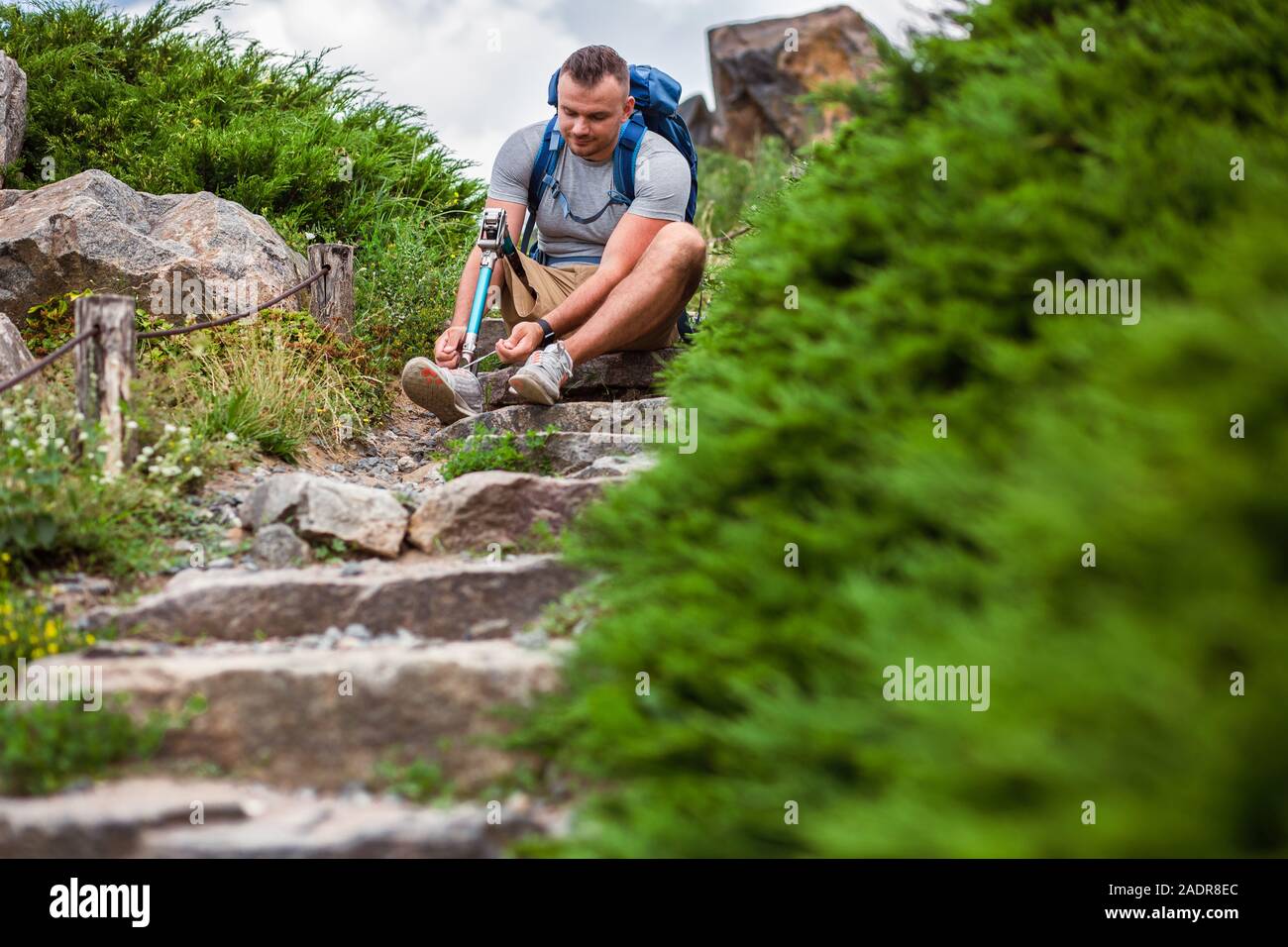 Pleasant man with prosthesis sitting on the stone stairs outdoors Stock Photo