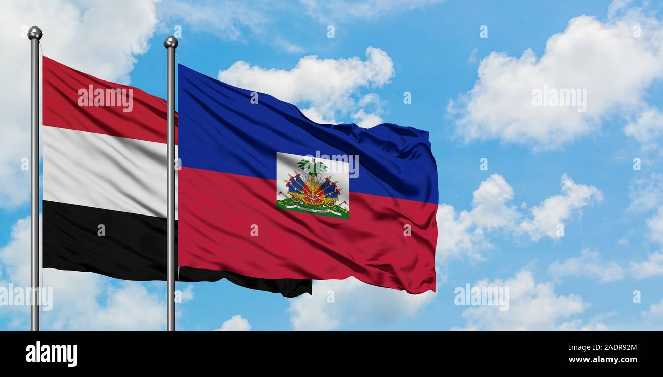 Yemen and Haiti flag waving in the wind against white cloudy blue sky together. Diplomacy concept, international relations. Stock Photo