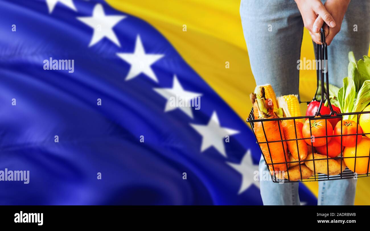 Woman is holding supermarket basket, Bosnia Herzegovina waving flag