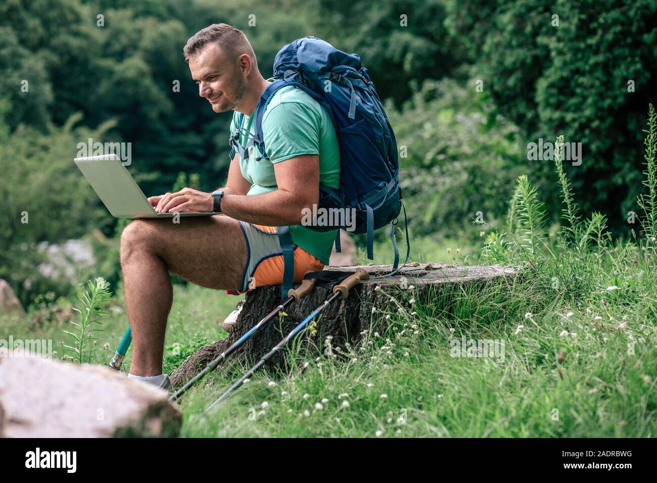 Cheerful man with prosthesis using his laptop outdoors Stock Photo