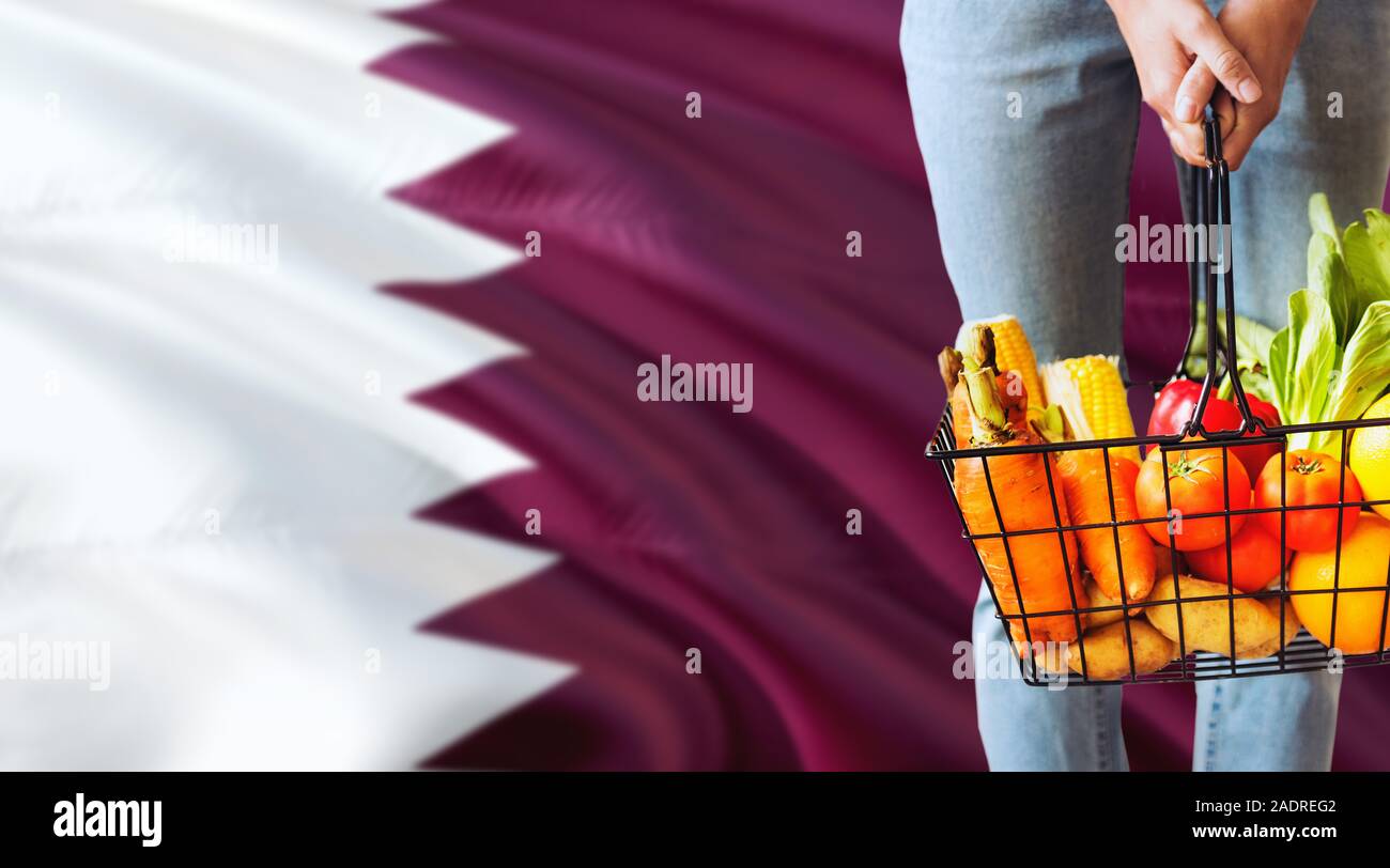 Woman is holding supermarket basket, Qatar waving flag background