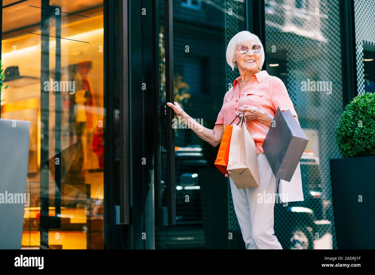 Delighted pensioner in sunglasses opening the door Stock Photo