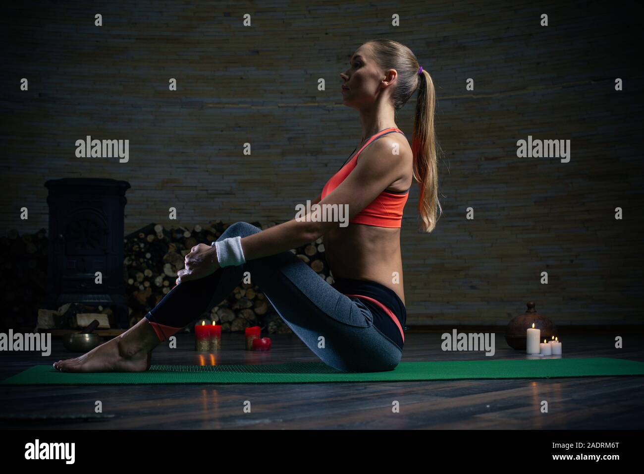 Long haired young lady sitting with straight back on the yoga mat Stock Photo