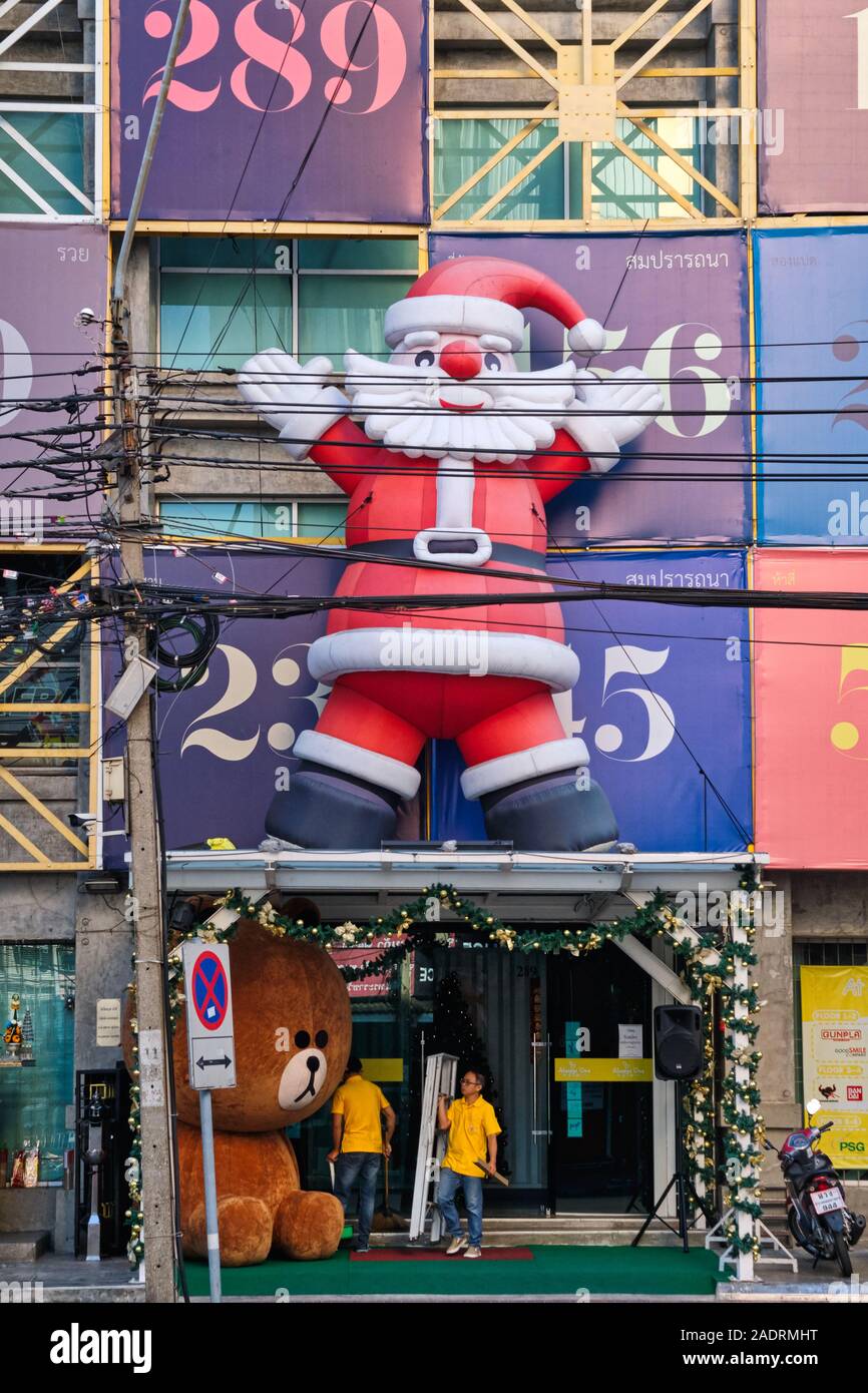 A large Santa Claus figure attached above the entrance of a small shopping plaza in Wang Burapha area, Bangkok, Thailand Stock Photo