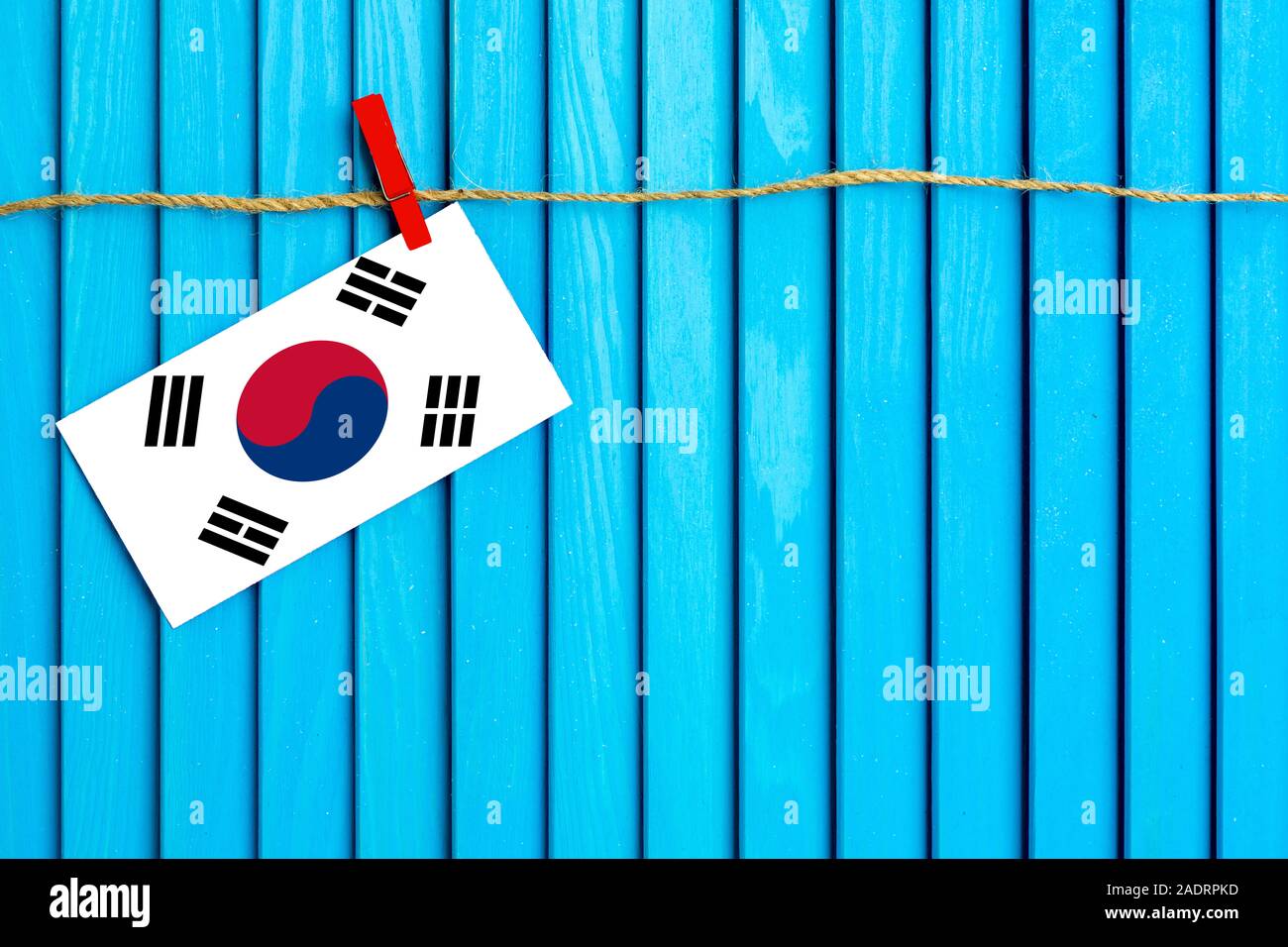 Flag of South Korea hanging on clothesline attached with wooden clothespins on aqua blue wooden