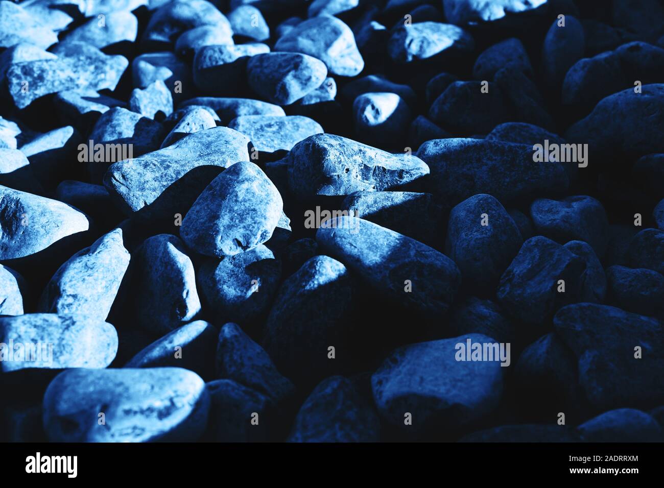Background of dark blue stones. Partually lighted with the sun. Color 2020. Stock Photo