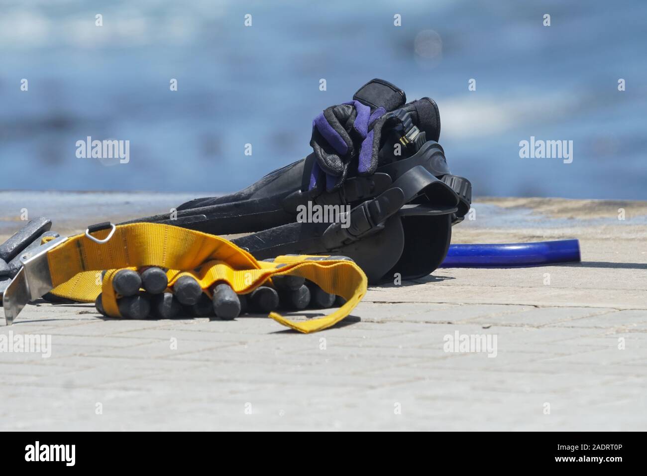 diving gear or dive equipment on the ground next to the sea or ocean with selective focus on the glove Stock Photo