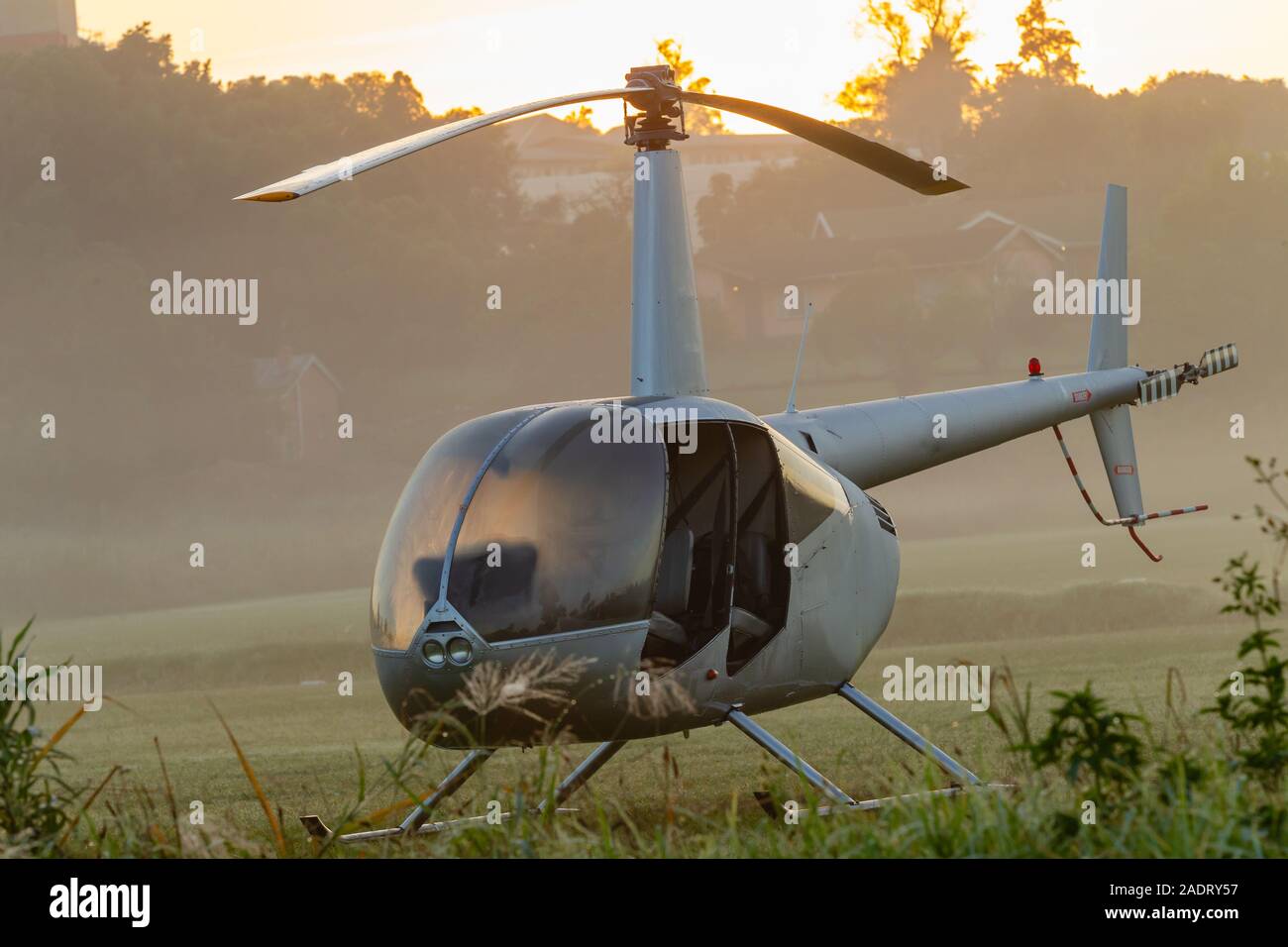 Helicopter small aircraft silver body open four seater turbine motor parked on grass field at dawn sunrise ready for sports event coverage Stock Photo Alamy