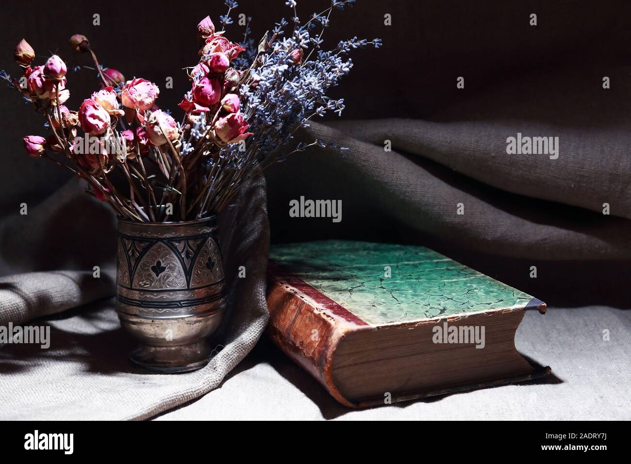Vintage still life with bouquet of dried flowers in a silver vase near ...