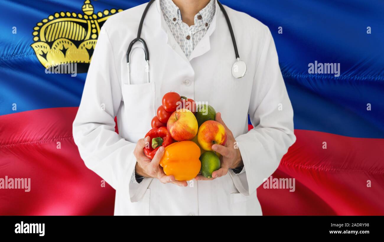 Doctor is holding fruits and vegetables in hands with Liechtenstein flag background. National healthcare concept, medical theme. Stock Photo