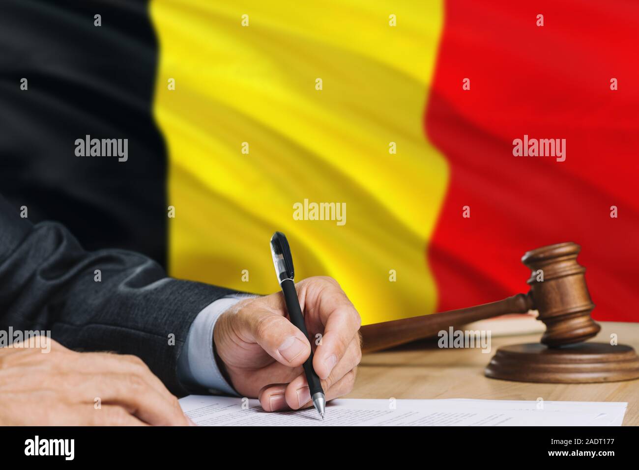 Judge writing on paper in courtroom with Belgium flag background. Wooden gavel of equality theme and legal concept. Stock Photo
