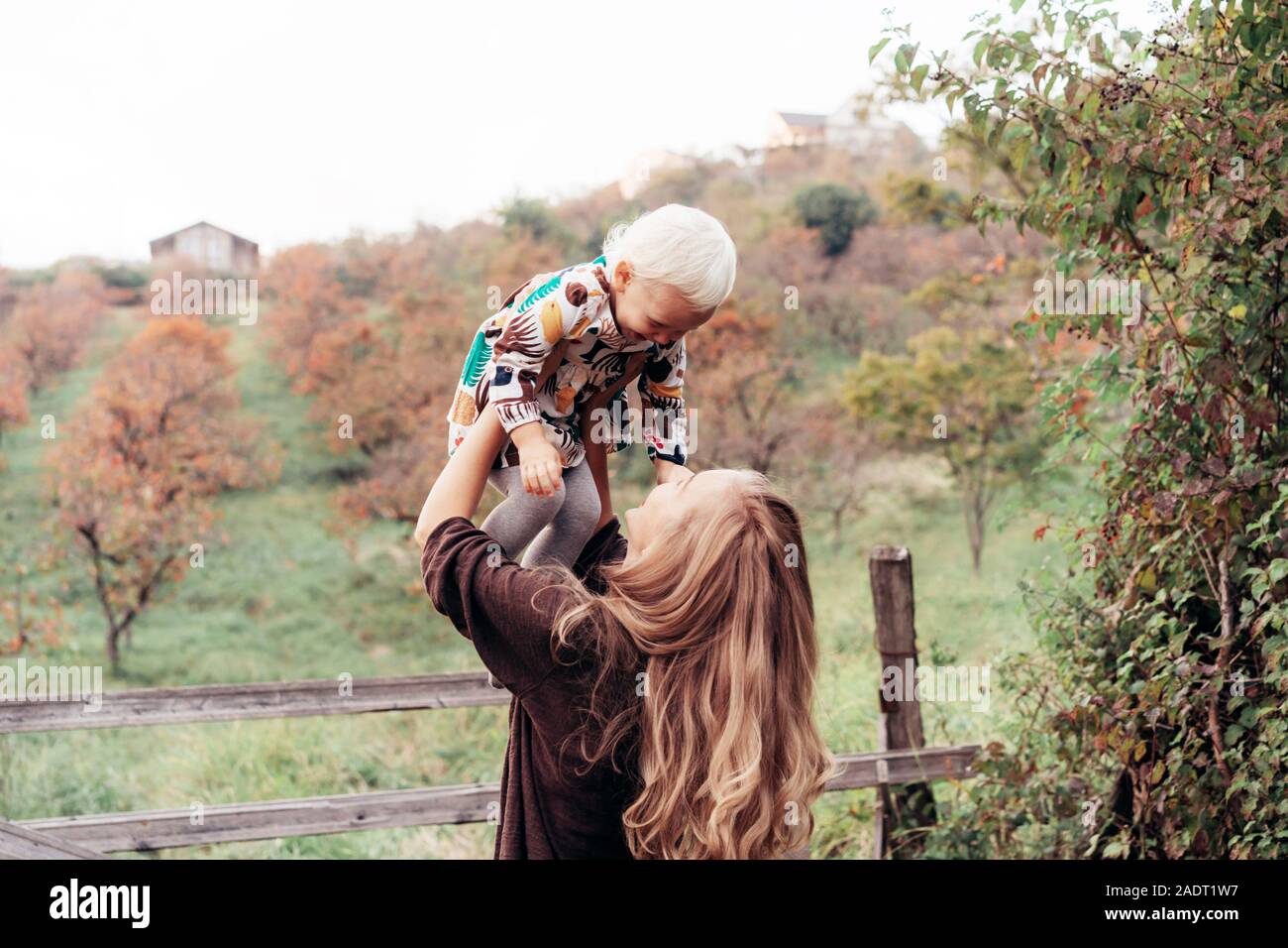 Mother throws up baby in the sky in autumn garden Stock Photo - Alamy