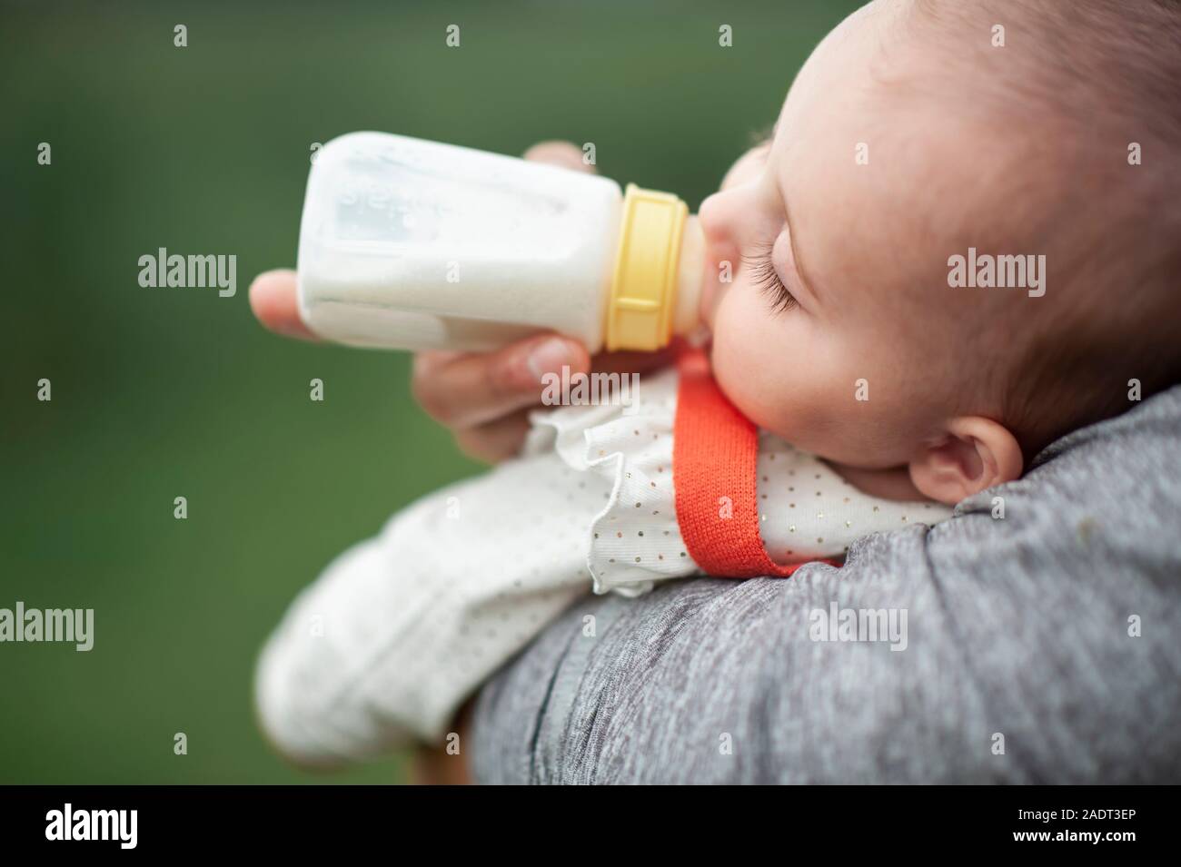 Baby girl sleeping while drinking a bottle outdoors Stock Photo Alamy