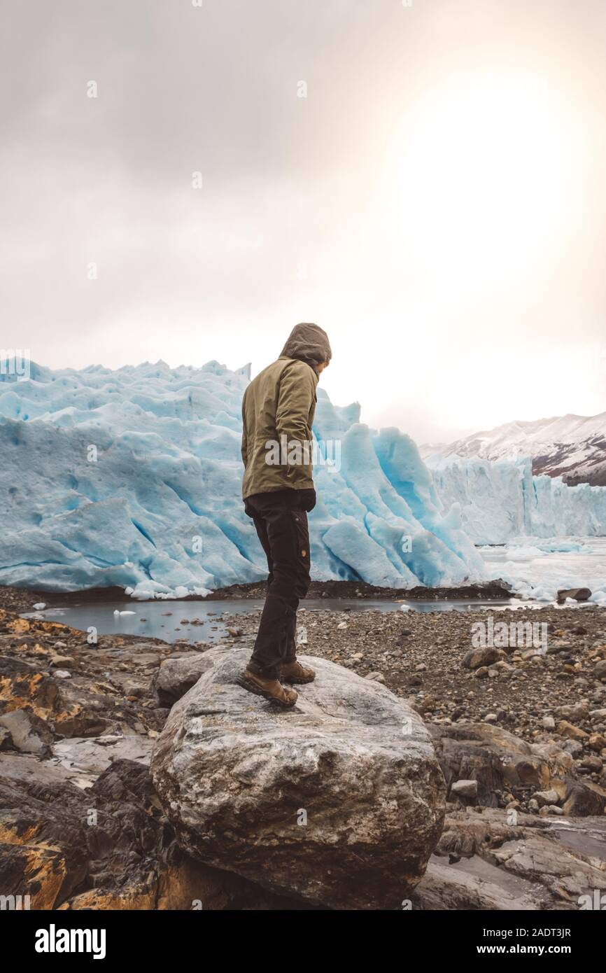 Unrecognizable man standing on boulder near glacier Stock Photo
