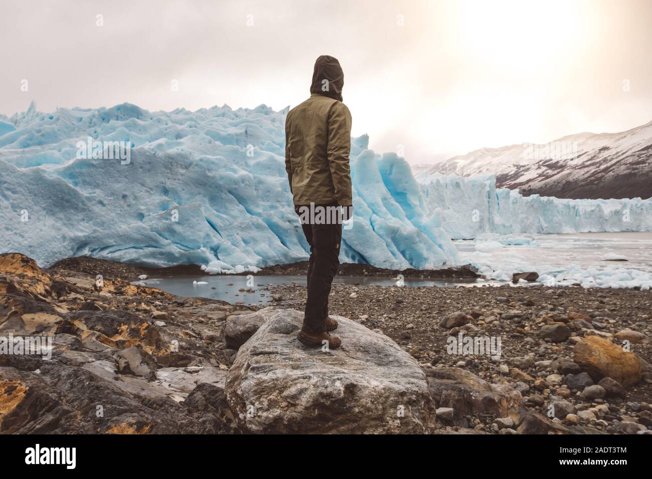 Unrecognizable man standing on boulder near glacier Stock Photo