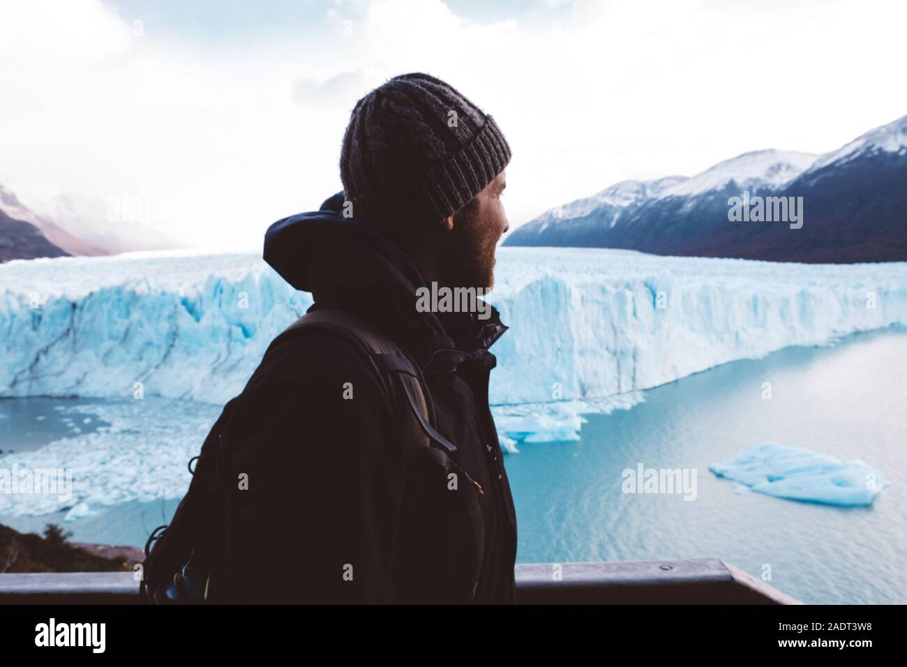 Male traveler near glacier on cloudy day Stock Photo
