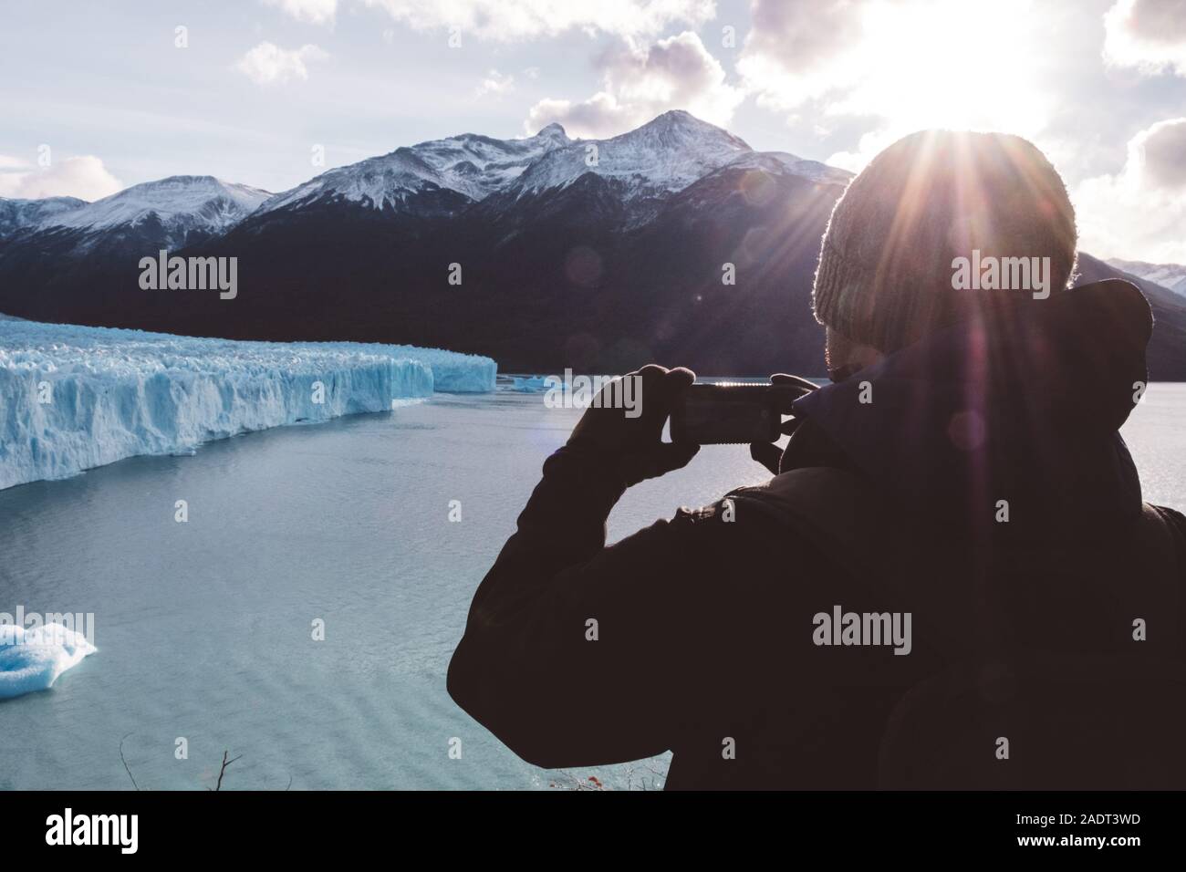 Male traveler taking a photo with a mobile near glacier on cloudy day Stock Photo
