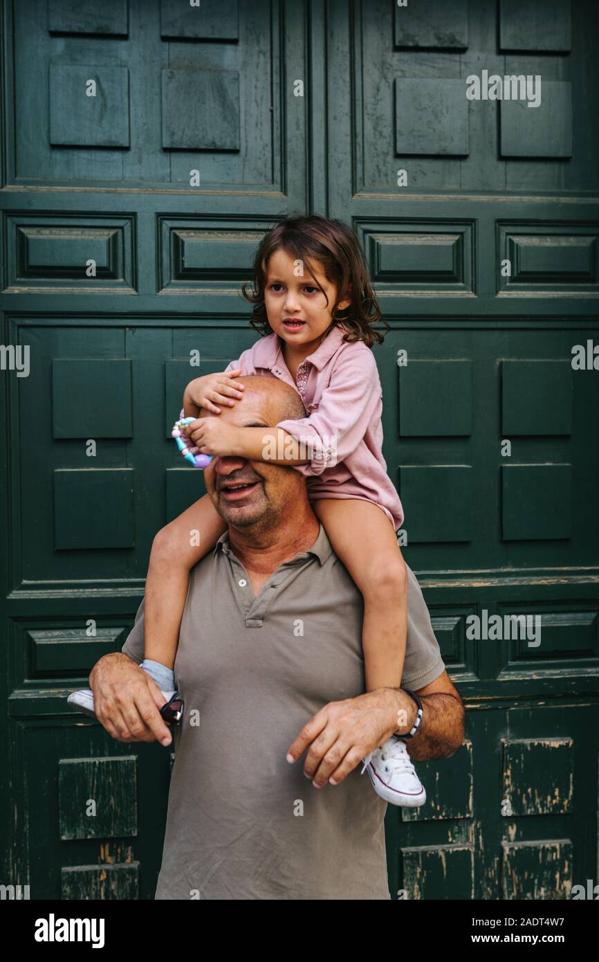 Grandfather with his granddaughter on his shoulders, playing, next to Stock Photo