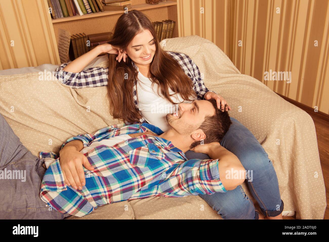 Handsome boy lying on girlfriend's legs on the sofa Stock Photo