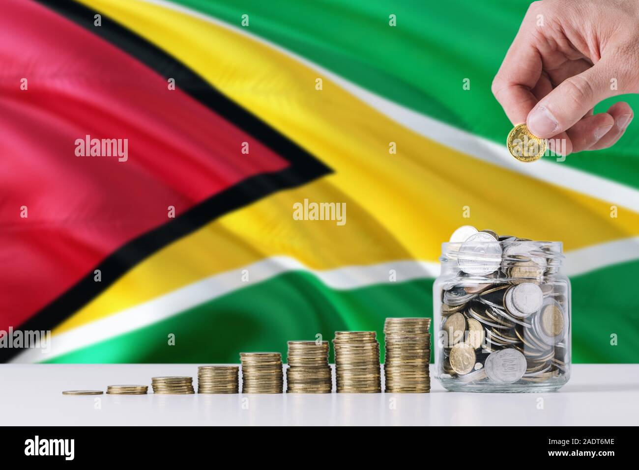 Business man holding coins putting in glass, Guyana flag waving in the ...