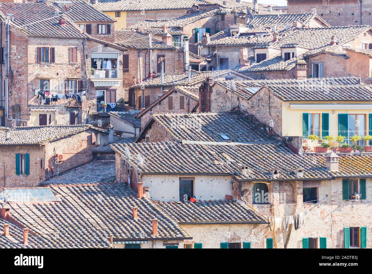 view on the roofs of the houses consisting of bricks and tiles creating the city architecture of Siena, Tuscany, Italy Stock Photo