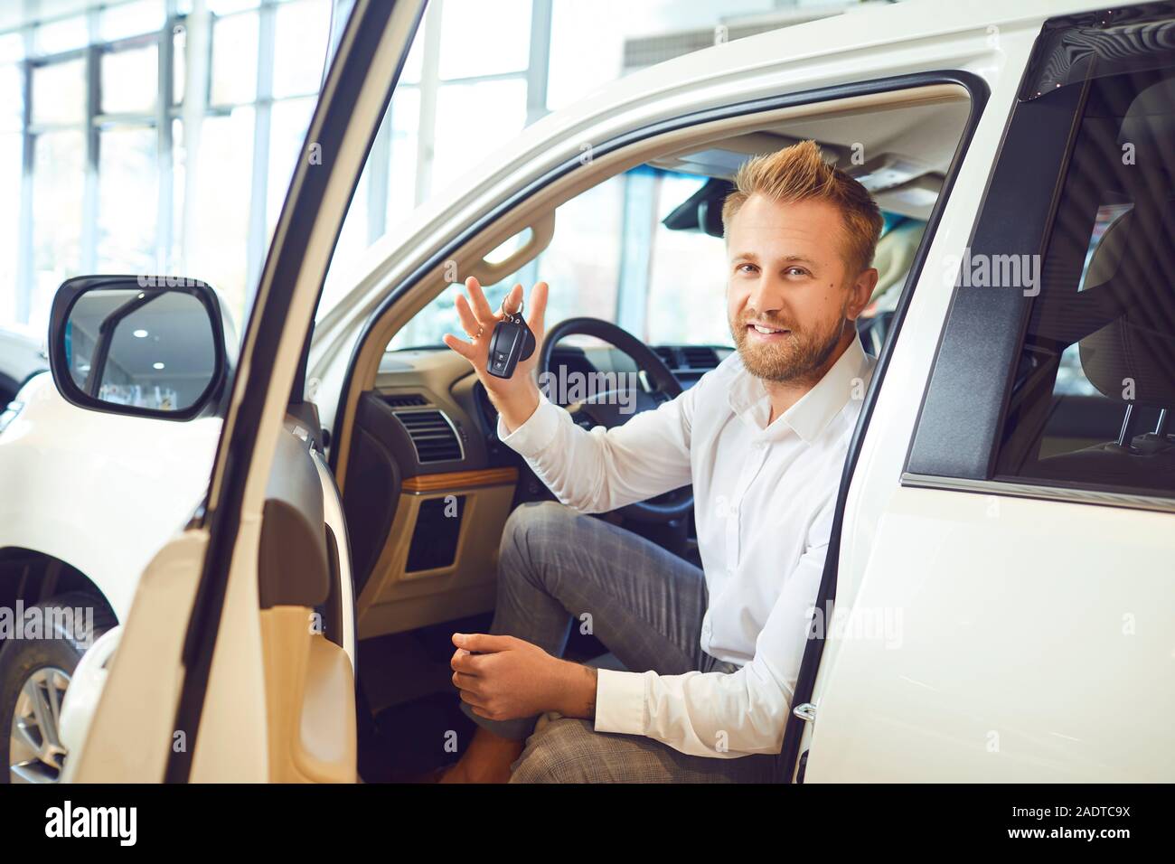 Auto buyer dealer man with keys in hand in a new car in auto salon. Stock Photo