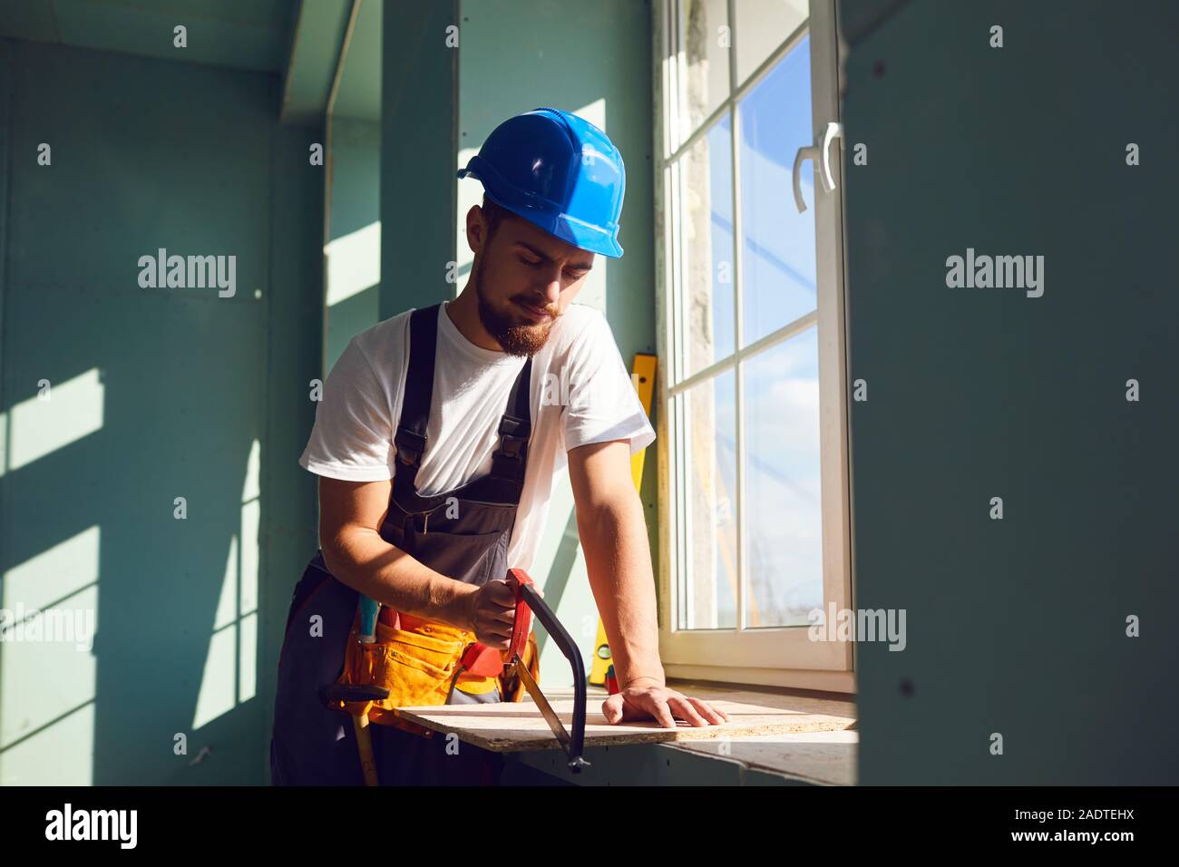 Builder contractor bearded man in helmet smiling while standing at a construction site. Stock Photo