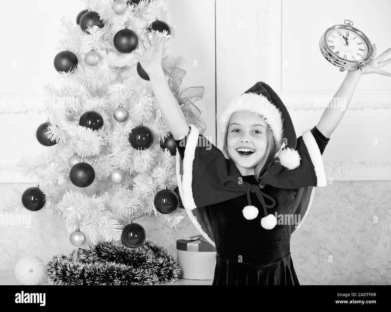 Last minute new years eve plans that are actually lot of fun. New year countdown. Girl kid santa hat costume with clock excited happy face counting time to new year. Last minute till midnight. Stock Photo