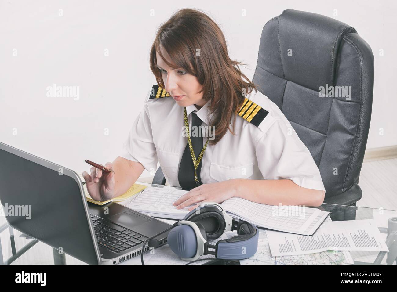 Beautiful woman pilot wearing uniform with epaulettes doing preflight briefing Stock Photo