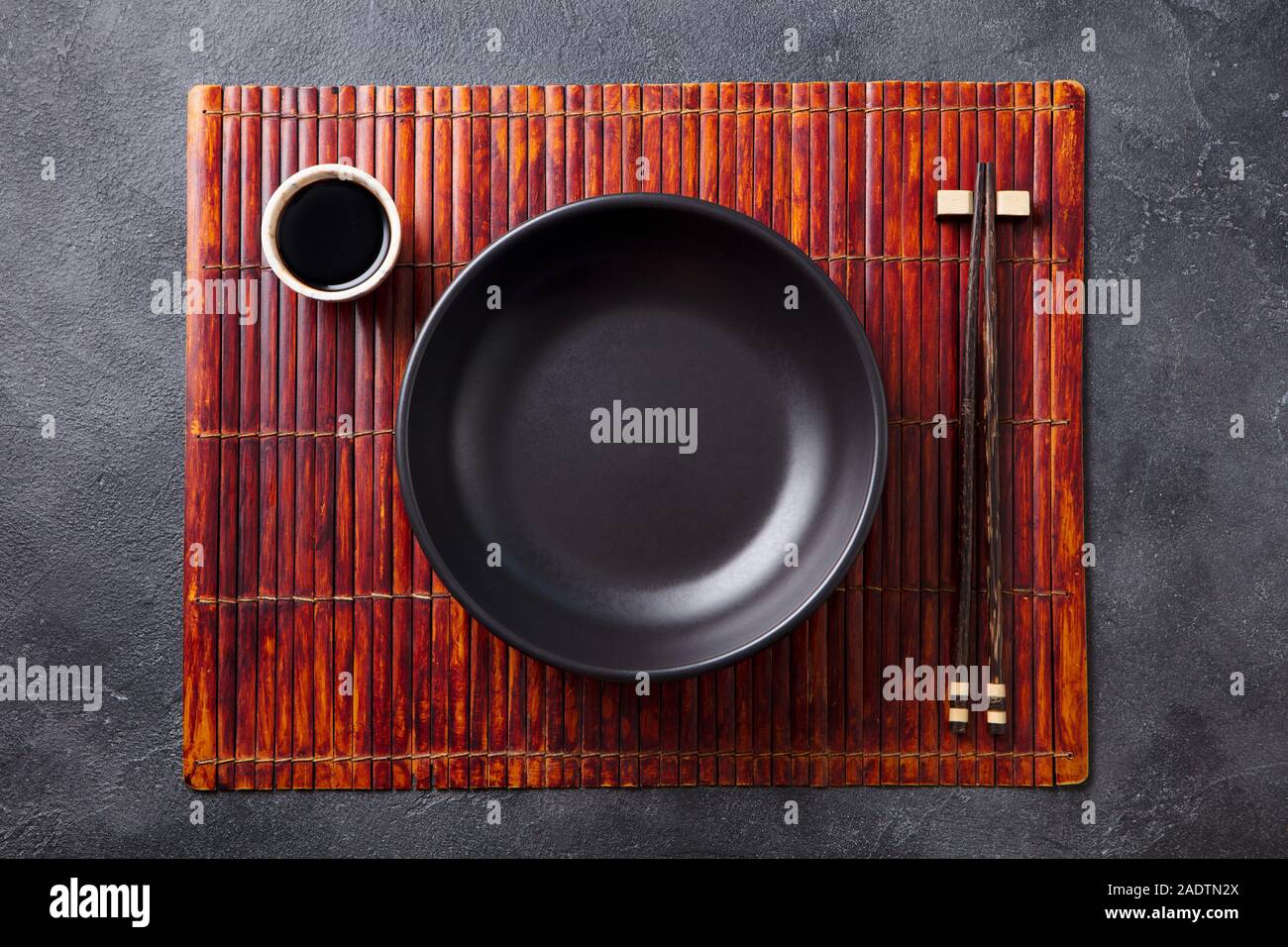 Asian table place setting with bamboo placemat, sauce bowl and chopsticks. Top view. Copy space