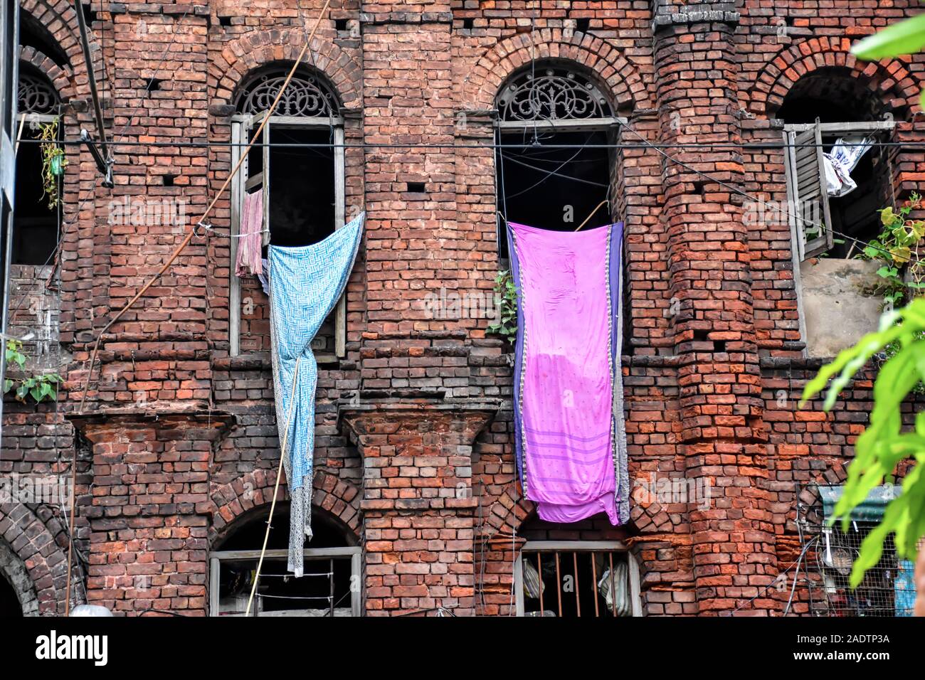 Clothes are hanging from the windows of a red brick wall vintage building Stock Photo