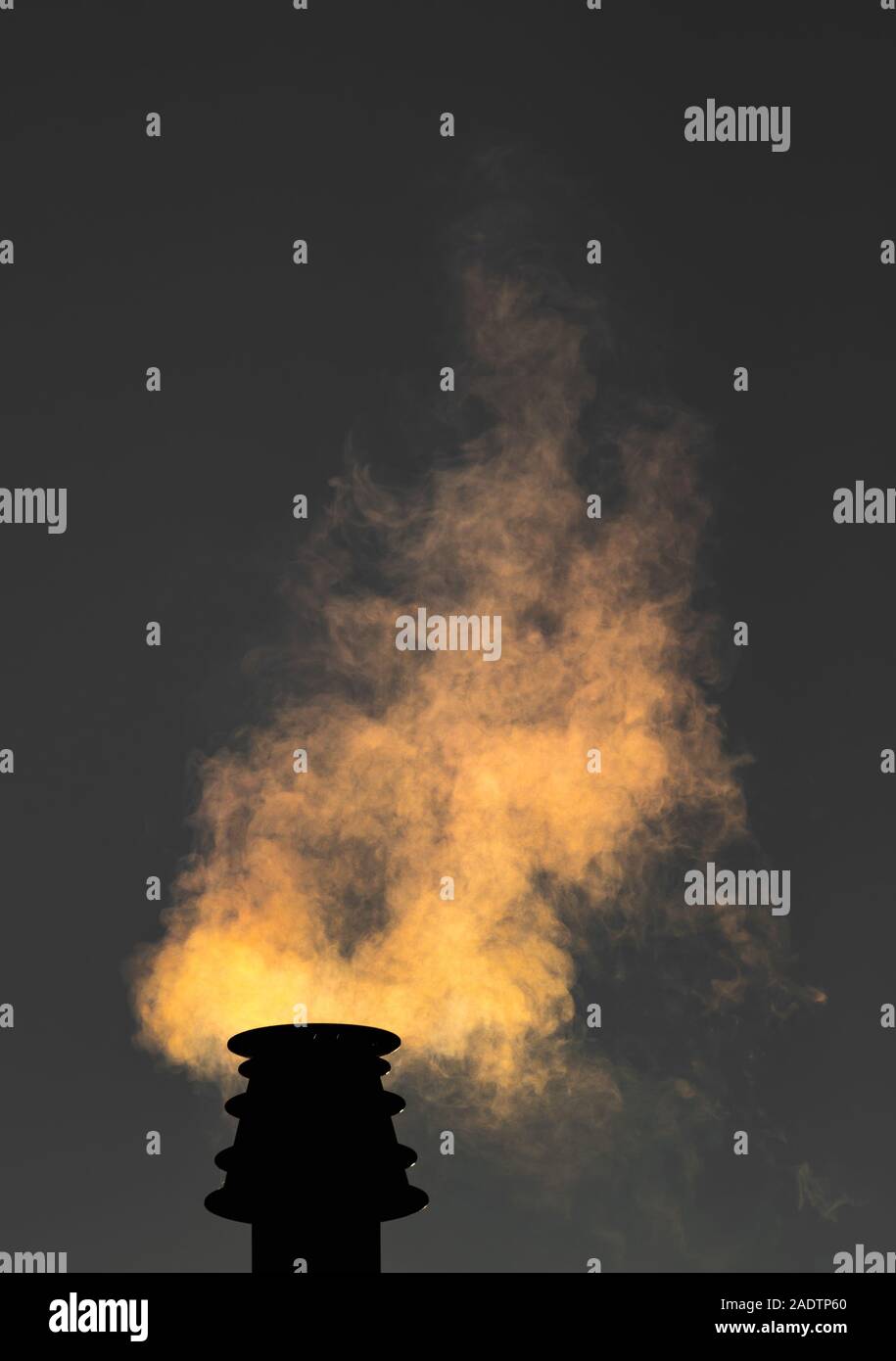 Smoke rising from a small chimney at night. Stock Photo