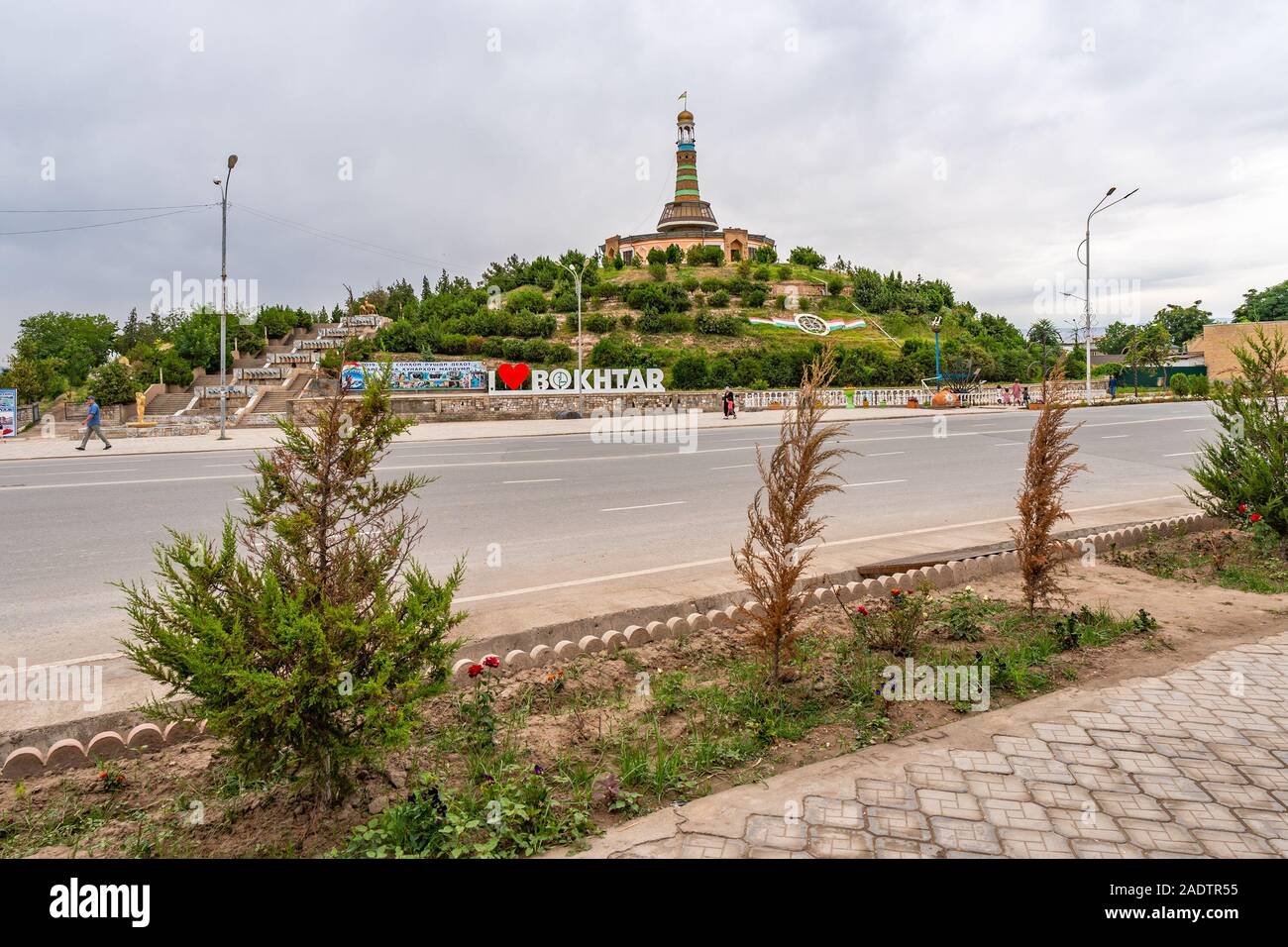 Qurghonteppa Bokhtar Bibikhonum Teppa Modern History Museum Monument Low Angle View with Waving Tajikistan Flag on a Cloudy Rainy Day Stock Photo