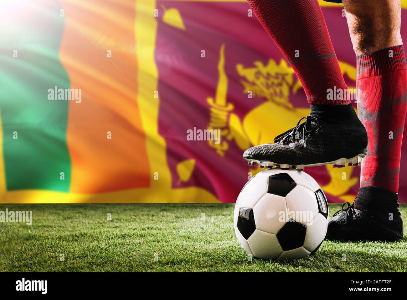 Close up legs of Sri Lanka football team player in red socks, shoes on soccer ball at the free kick or penalty spot playing on grass. Stock Photo