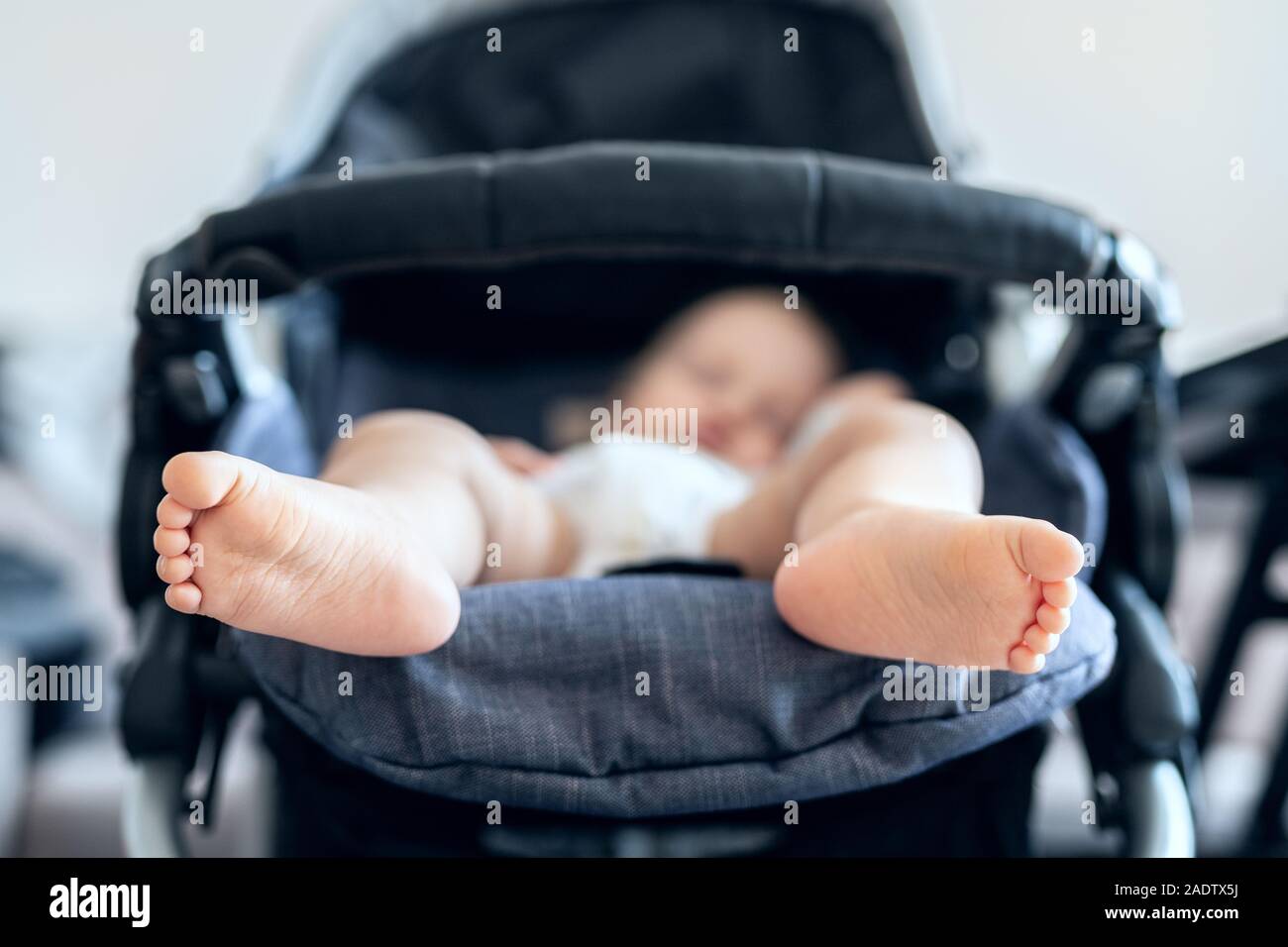 Cute adorable caucasian blond toddler bou sleeping in stroller at daytime. Children healthcare and happy childhood concept Stock Photo