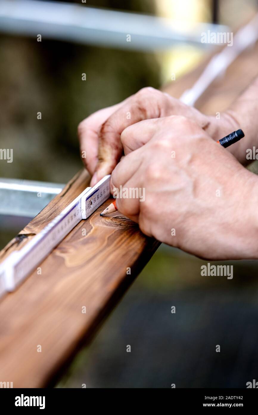 Close-up of hands, wooden plank is measured with the help of a yardstick and made a mark with a pencil Stock Photo
