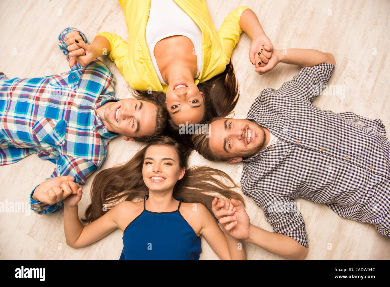 Young People Lying On The Floor Holding Hands Stock Photo