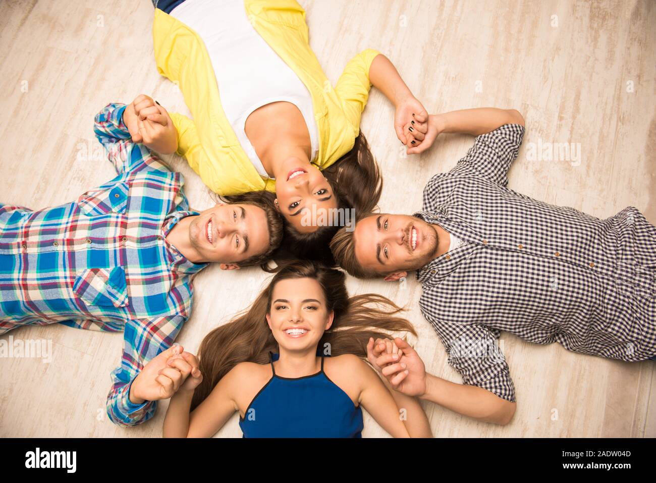 Young People Lying On The Floor Holding Hands Stock Photo