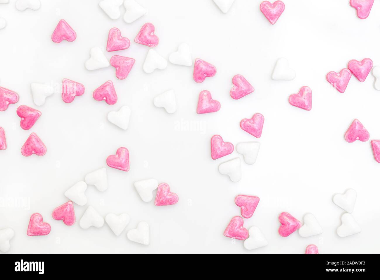 sugar hearts colored white and pink, spreading on white background, concept love card Stock Photo